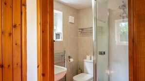 A bathroom with a glass shower enclosure, a white toilet, and a sink with a towel rack. - Swift Host Barn Cottage Rural Barn near the Norfolk Broads (Norfolk Broads)
