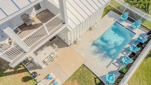 A modern building with a swimming pool, outdoor seating, and a fenced area. - The Flagship | Private Pool | BoardWalk|*GAME ROOM* (Port Aransas)