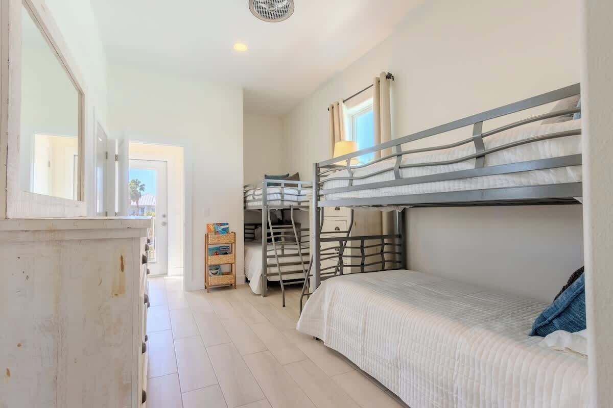 Een slaapkamer met een stapelbed, een raam, een klein houten kastje en een ladder.