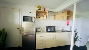 Een kleine keuken met een koelkast, magnetron, broodrooster en een spoelbak.