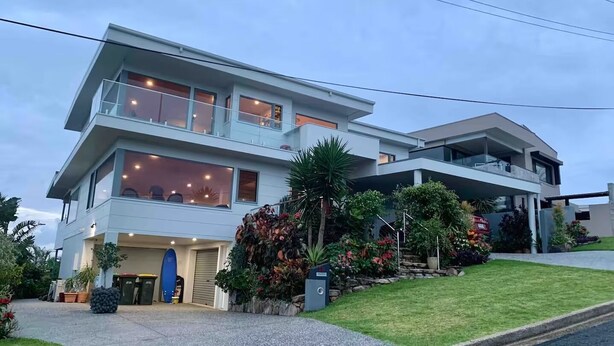 Een modern herenhuis met garage, grote ramen en een verzorgde tuin.