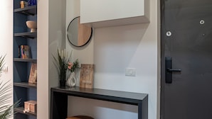 A modern interior with a dark wooden floor, a black console table, a brown ottoman, a white wall-mounted cabinet, and a dark door. - Trendy & Private City Studios Near Cismigiu & Calea Victoriei (Bucharest)