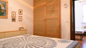 Een slaapkamer met een bed, een houten garderobe en afbeeldingen in lijsten aan de muur.