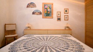 Een slaapkamer met een bed, een stoel, een nachtkastje met lampen en kunst aan de muur.