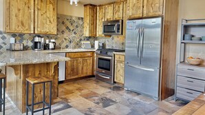 Una cocina con armarios de madera, un refrigerador de acero inoxidable, un microondas, una estufa y una cafetera.