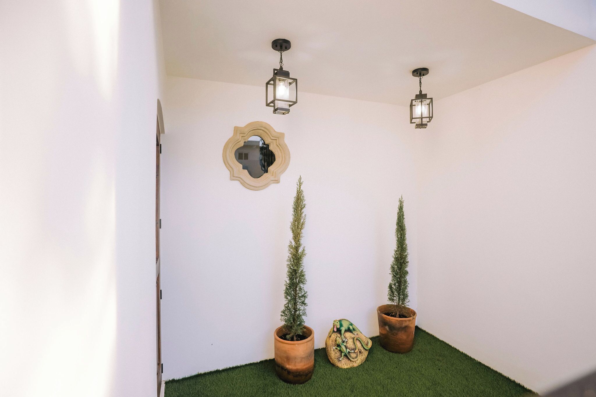 Un couloir orné de deux plantes en pot, d’un miroir décoratif et de deux lanternes suspendues.