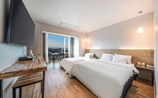 Une chambre d’hôtel avec deux lits, un bureau, une télévision et une vue sur la ville.