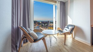 A modern room with a large window, two chairs, a small table, and a view of the cityscape. - Incheon The Rest Hotel (Incheon)