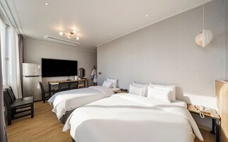 A hotel room with two beds, a desk, a flat-screen TV, a mirror, a lamp, and a telephone.