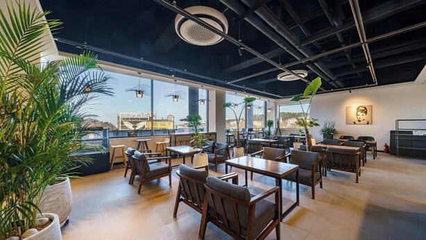 An indoor dining area with tables and chairs, large windows, and potted plants. - Incheon The Rest Hotel (Incheon)