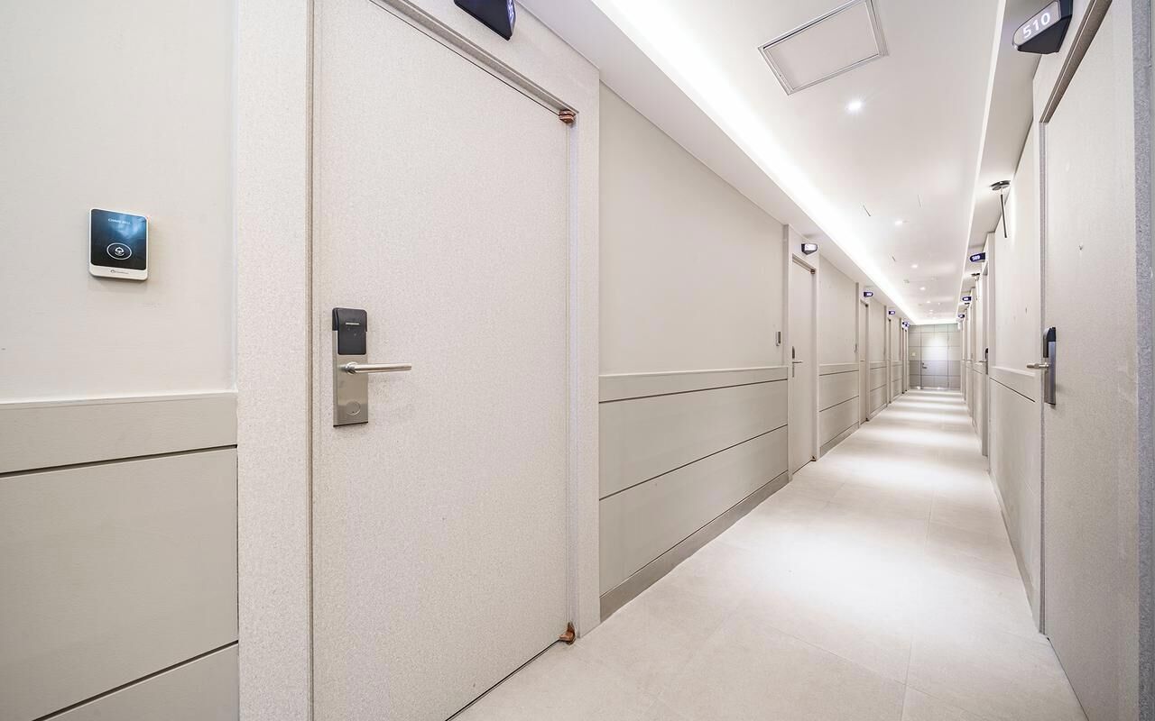 A hotel corridor with doors, a digital lock, and a number sign.