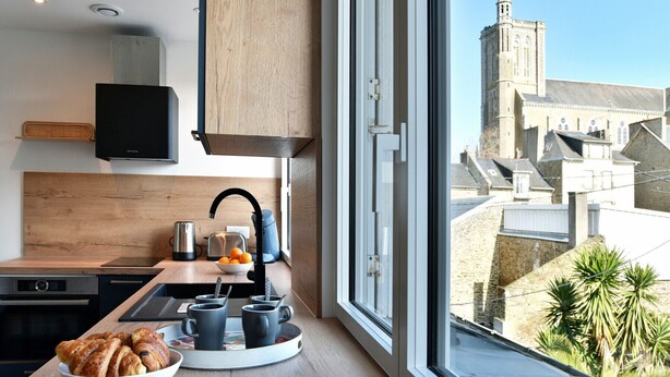A modern kitchen with a view of a historic tower. - La Plage du Petit Port (Cancale)