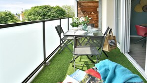 En balkon med et bord dækket til to personer, et magasin og et par solbriller på bordet.