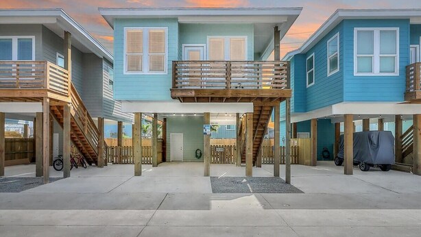 A row of beach houses with wooden balconies, a covered parking area, and a view of the ocean. - B3 Beach House | Private Pool (Port Aransas)