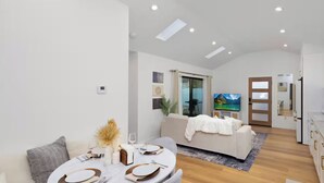 A modern, well-lit living room with a dining area, a sofa, and a TV. - Modern House in Culver City Santa Monica (Culver City)