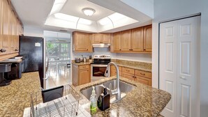A modern kitchen with granite countertops, stainless steel appliances, and wooden cabinets. - Private Pool Oasis near Parks (Port Charlotte)