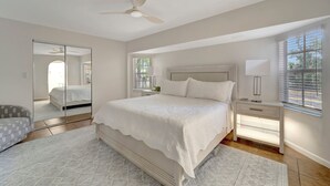 A bedroom with a bed, bedside tables, a mirror, and a ceiling fan. - Private Pool Oasis near Parks (Port Charlotte)