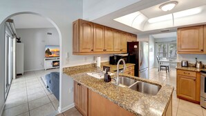 A modern kitchen with granite countertops, wooden cabinets, and a built-in microwave. - Private Pool Oasis near Parks (Port Charlotte)