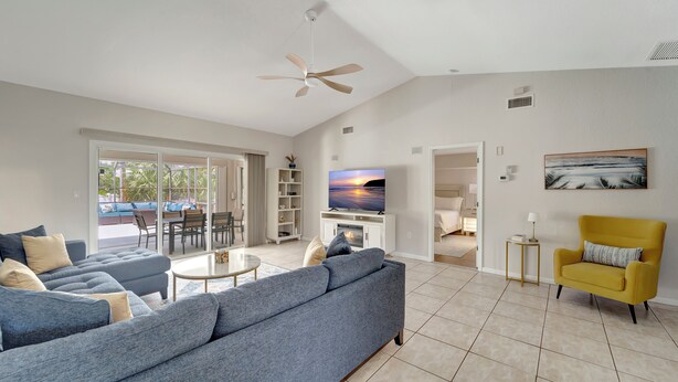 A spacious living room with a large sofa, a yellow armchair, and a television. - Private Pool Oasis near Parks (Port Charlotte)