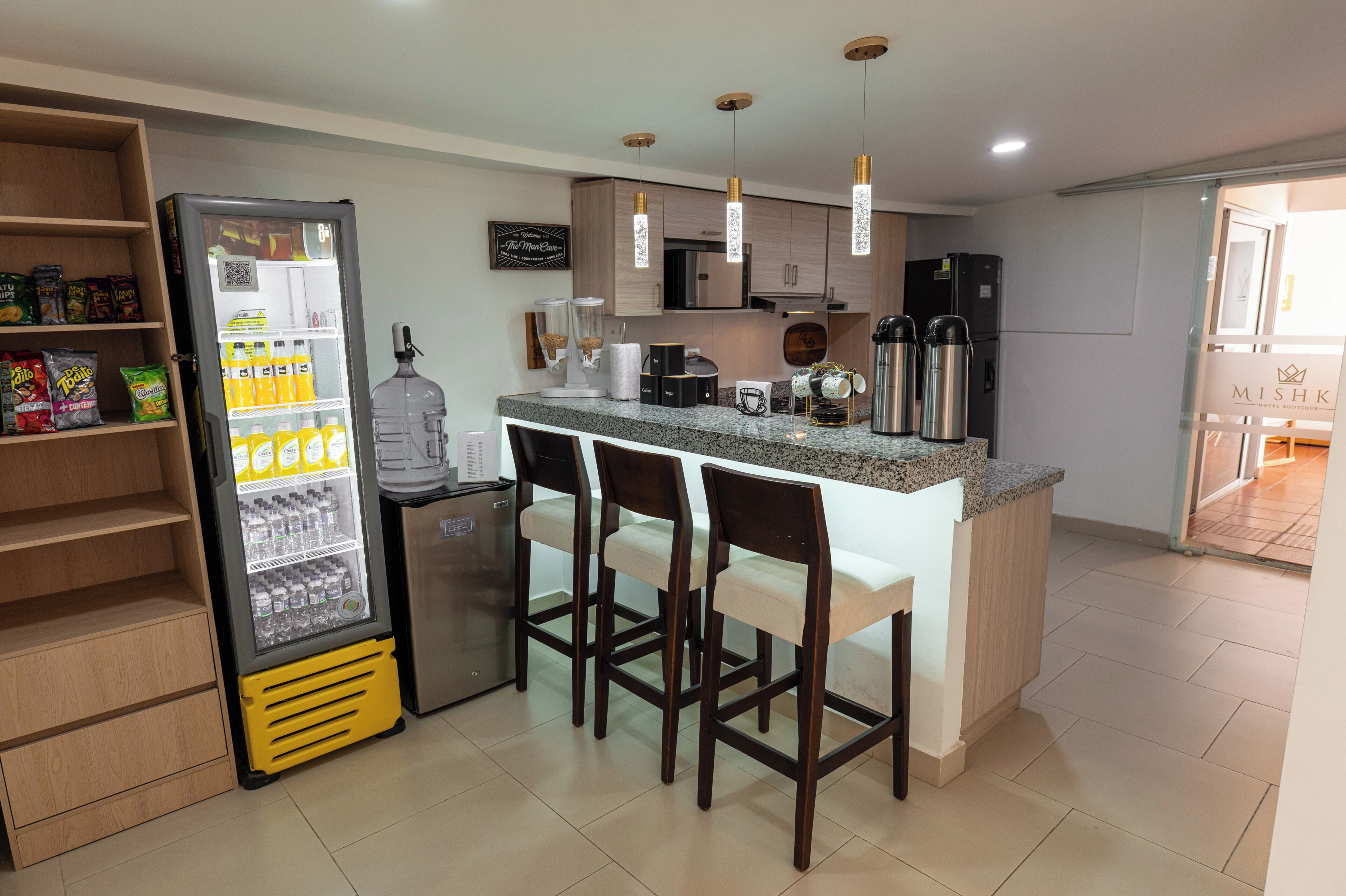 Una cocina moderna con refrigerador, dispensador de agua, taburetes de bar y máquina de café.