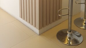 Uma área de recepção com balcão de madeira, um banquinho e uma estátua de uma figura segurando uma criança.