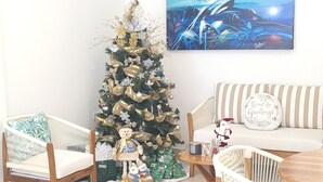 Uma sala de estar com uma árvore de Natal, um relógio e um quadro.