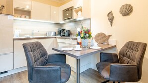 Une cuisine moderne dotée d’un coin repas, comprenant deux chaises rembourrées, une table à manger et un comptoir de cuisine avec des appareils électroménagers.