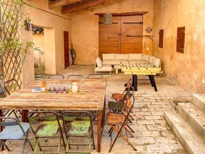 An outdoor patio with a wooden table, chairs, a sofa, and a foosball table. - Between Mont Ventoux and Luberon, air-conditioned Provencal farmhouse with swimming pool, indoor... (MAZAN)