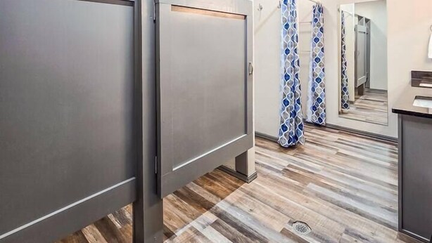 A modern bathroom with a shower, a mirror, and a wooden floor. - Angler Hideaway | Belle Starr Marina | Pool | Fish (Checotah)