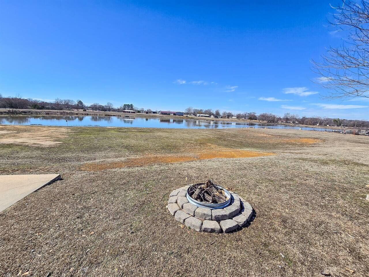 Una fogata en un área de césped con un lago al fondo.