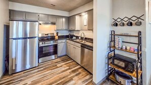 A modern kitchen with stainless steel appliances, wooden flooring, and a coffee station. - Angler Hideaway | Belle Starr Marina | Pool | Fish (Checotah)