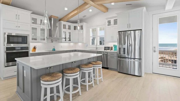 A modern kitchen with a large island, stainless steel appliances, and a view to the outside.