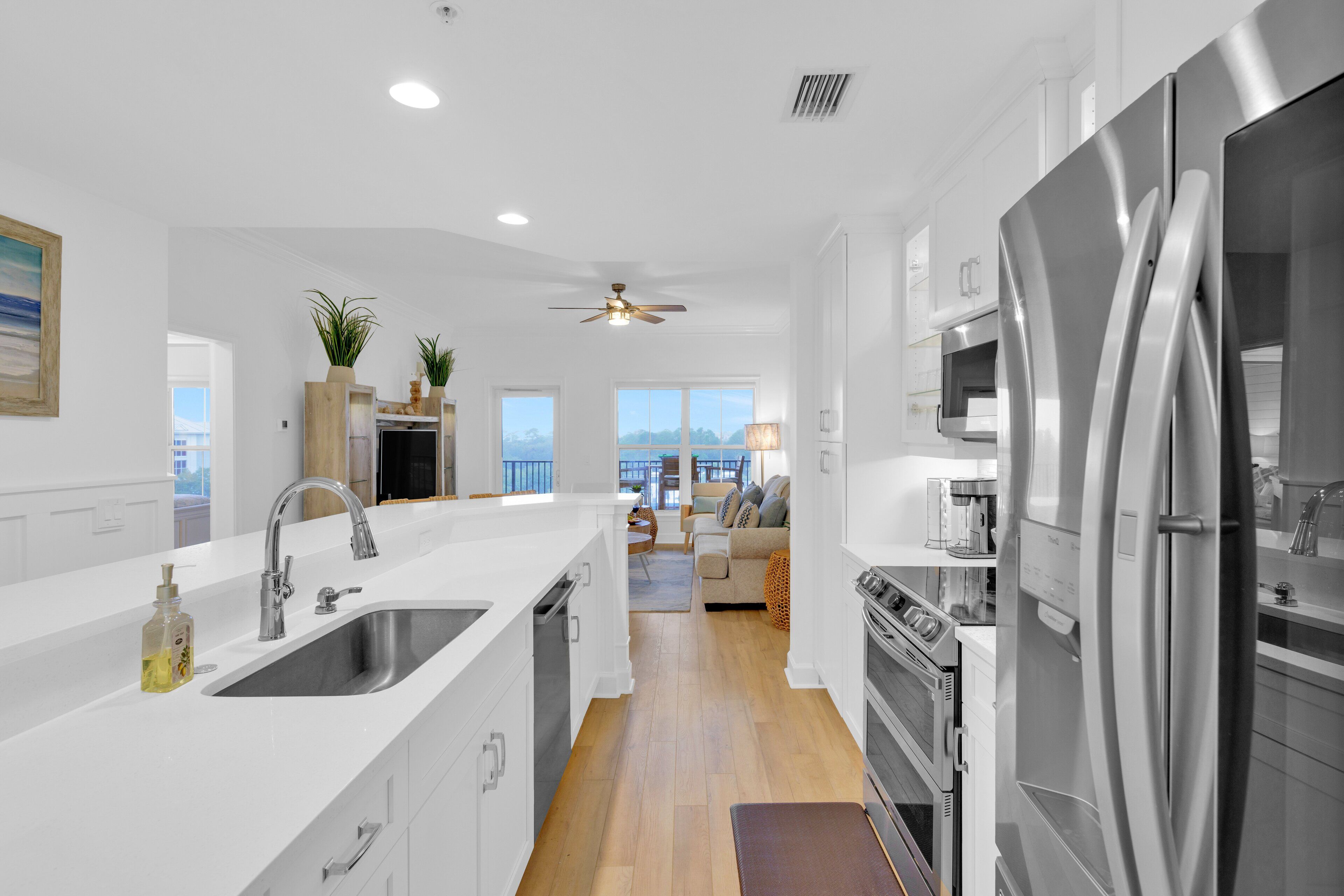 A modern kitchen with a large stainless steel refrigerator, a sink, and a ceiling fan.