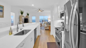 Una cocina moderna con un refrigerador de acero inoxidable grande, un lavamanos y un ventilador de techo.
