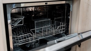 An open dishwasher with racks and utensils inside. - Grunwald Raszyńska Studio (Poznań)