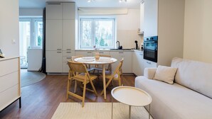 A modern kitchen with a dining area, a sofa, and a small table.