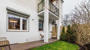 A modern building with a balcony, outdoor seating, and a well-maintained garden.