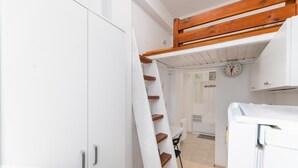 A narrow hallway with a white wardrobe, a wooden ladder, and a white radiator.