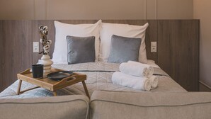 A neatly made bed with a quilted cover, two pillows, a tray with a mug and a plate, and a vase with dried flowers. - Puerto 7 Stylowe Studio z Tarasem Doskona y Komfort (Bydgoszcz)