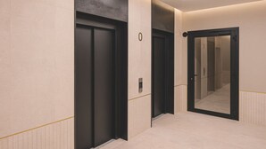A modern hallway with two elevators and a mirrored wall. - Puerto 7 Stylowe Studio z Tarasem Doskona y Komfort (Bydgoszcz)