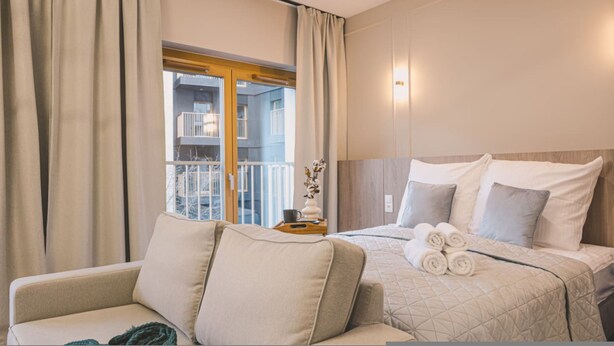 A hotel room with a bed, a sofa, and a window with curtains. - Puerto 7 Stylowe Studio z Tarasem Doskona y Komfort (Bydgoszcz)