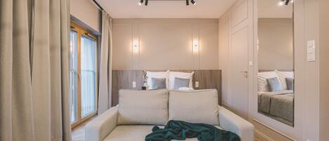 Una habitación de hotel moderna con un sofá, una mesita redonda y un espejo en la pared.