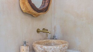 Un bagno con uno specchio di legno originale, un lavabo in pietra e un rubinetto in ottone.