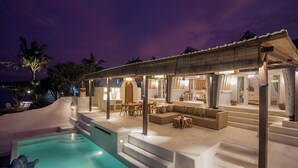 Un resort moderno con piscina, area salotto all'aperto e zona pranzo coperta.
