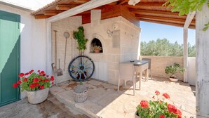 Un espacio al aire libre cubierto con un muro de piedra, una mesa de madera y plantas en macetas.