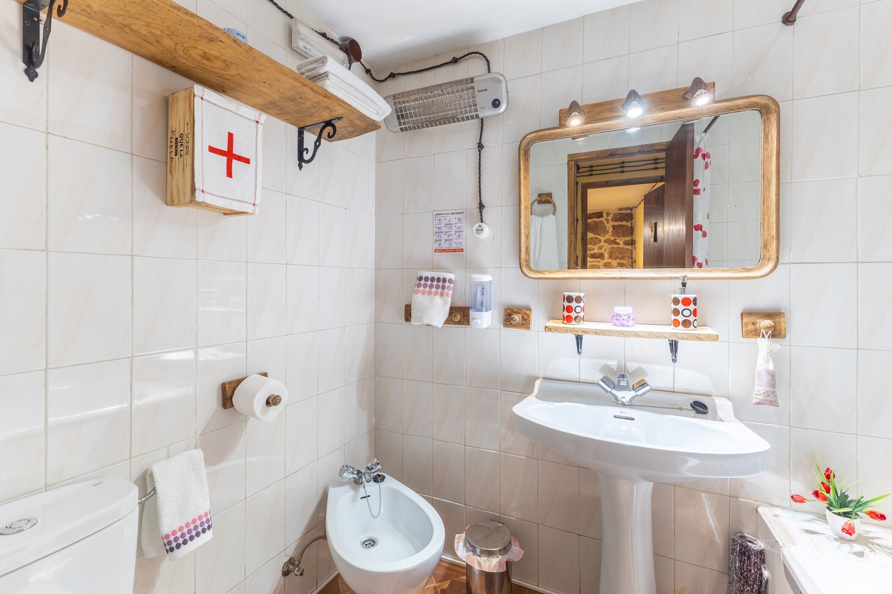 A bathroom with a white sink, a bidet, a mirror, and a towel rack.