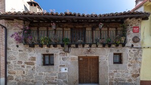 Edifici de pedra amb una porta de fusta, un balcó ple de plantes i un cartell que diu 'Anovel'.