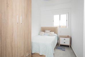 Ein Schlafzimmer mit einem Bett, einem Nachttisch, einem Holzschrank und einem Fenster.