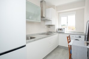 A kitchen with a microwave, washing machine, and a window.