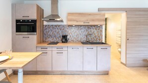 Una cocina moderna con horno empotrado, cafetera y fregadero.